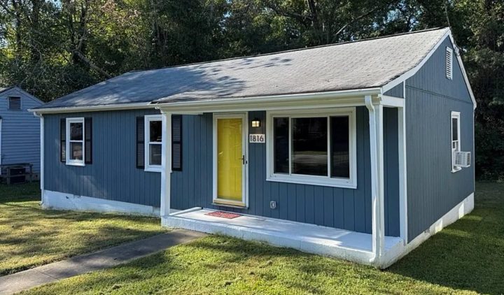 Front view of a blue house single story house with a yellow door, a successful Borrower rehab project funded by Marie William Capital.